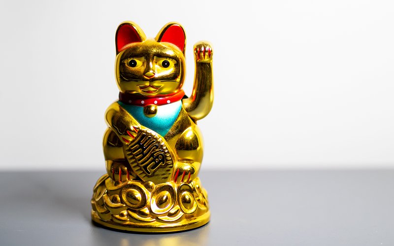 Golden lucky cat with left paw raised symbolizing invitation