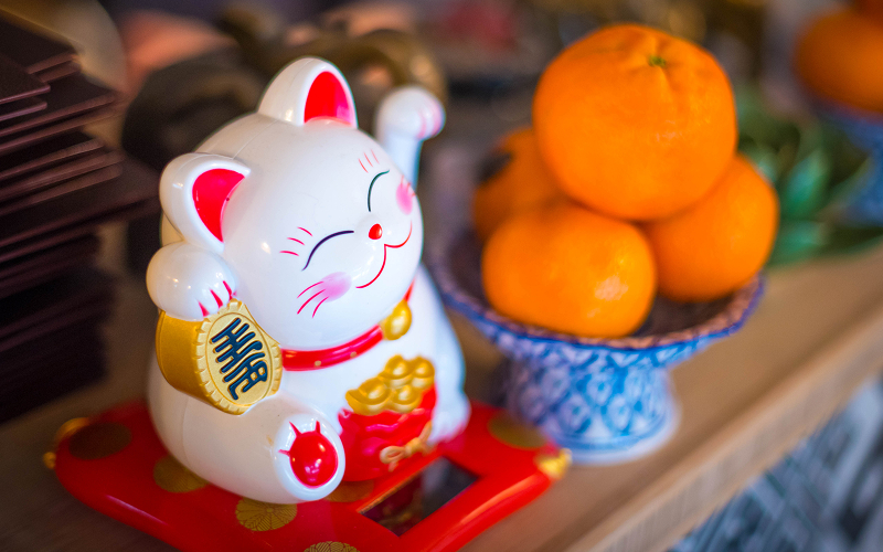 Japanese fortune cat displayed next to mandarins at home.