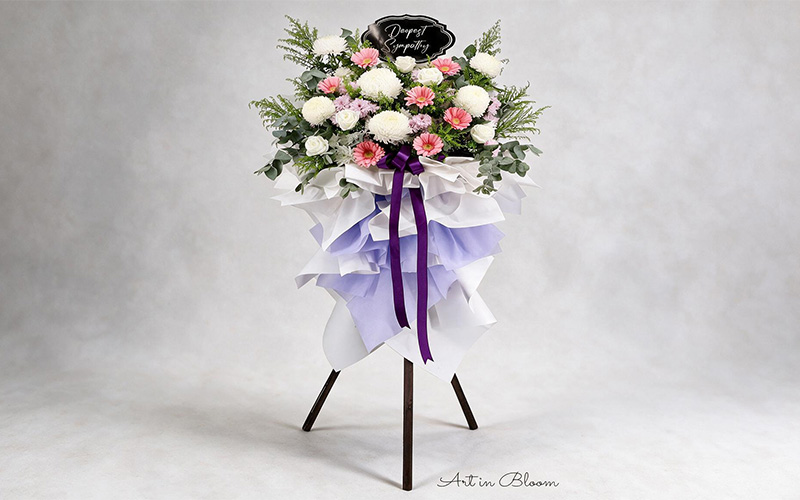 Traditional condolence funeral flower wreath display on a tripod stand.