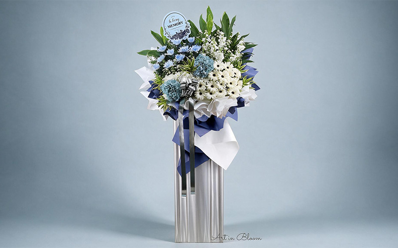 Custom blue and white funeral flower arrangement for personal tribute.
