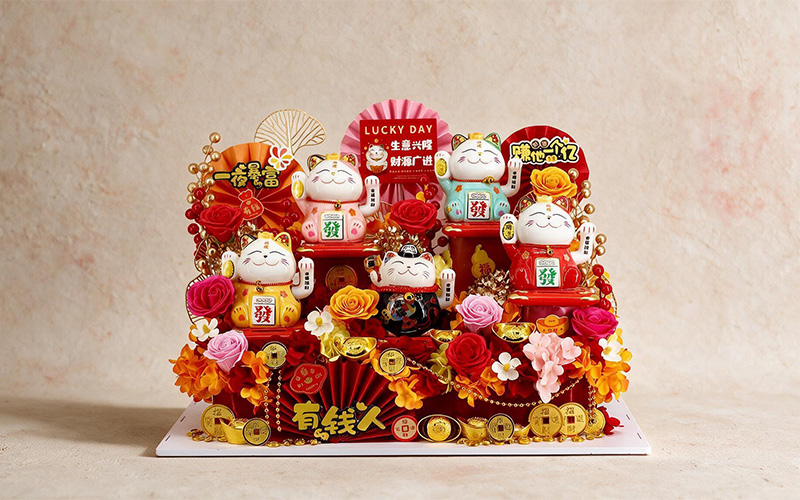 Traditional calico Maneki-neko lucky cats featured with festive floral arrangement.